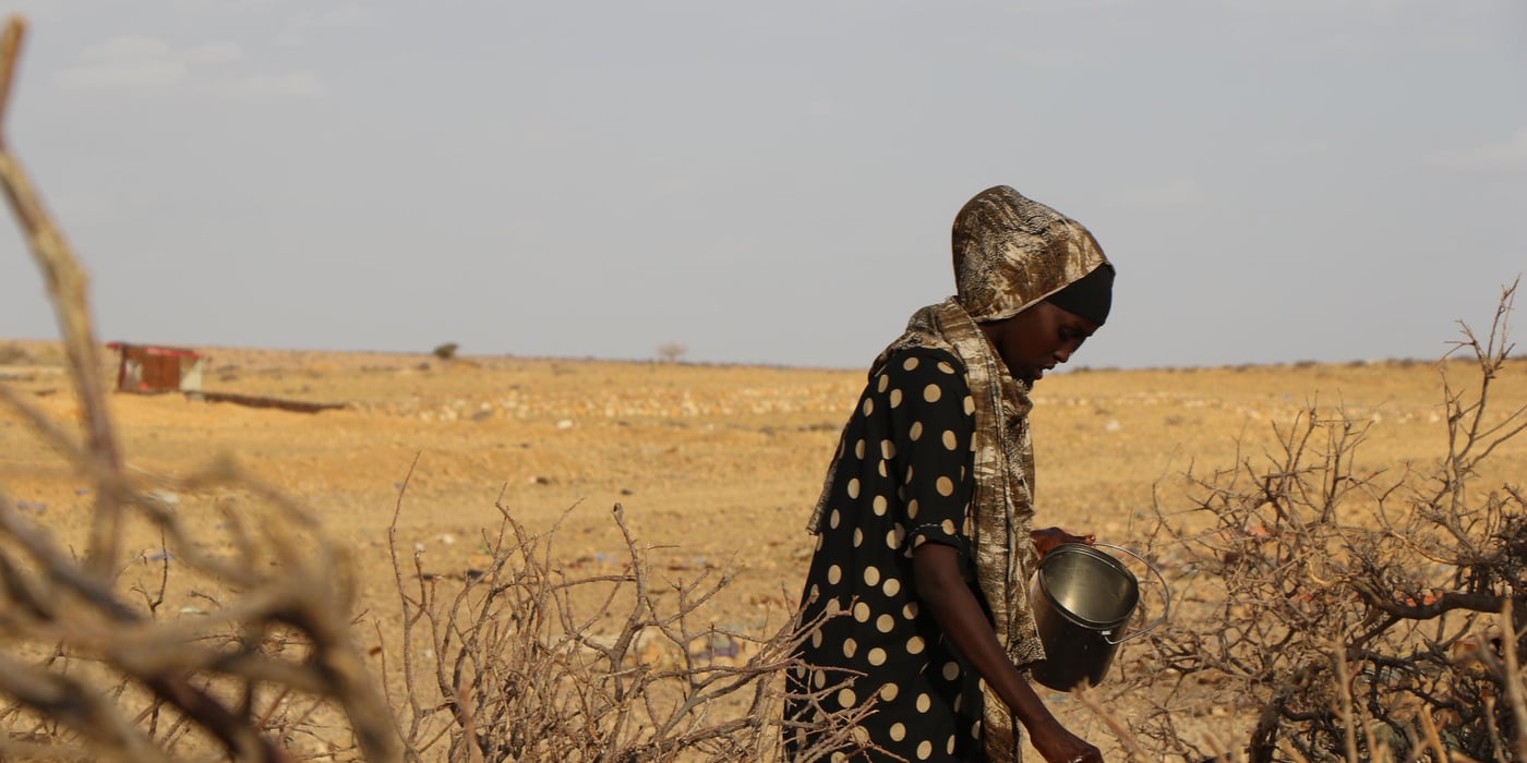 Woman filling pots with water from a yellow jerrycan.
