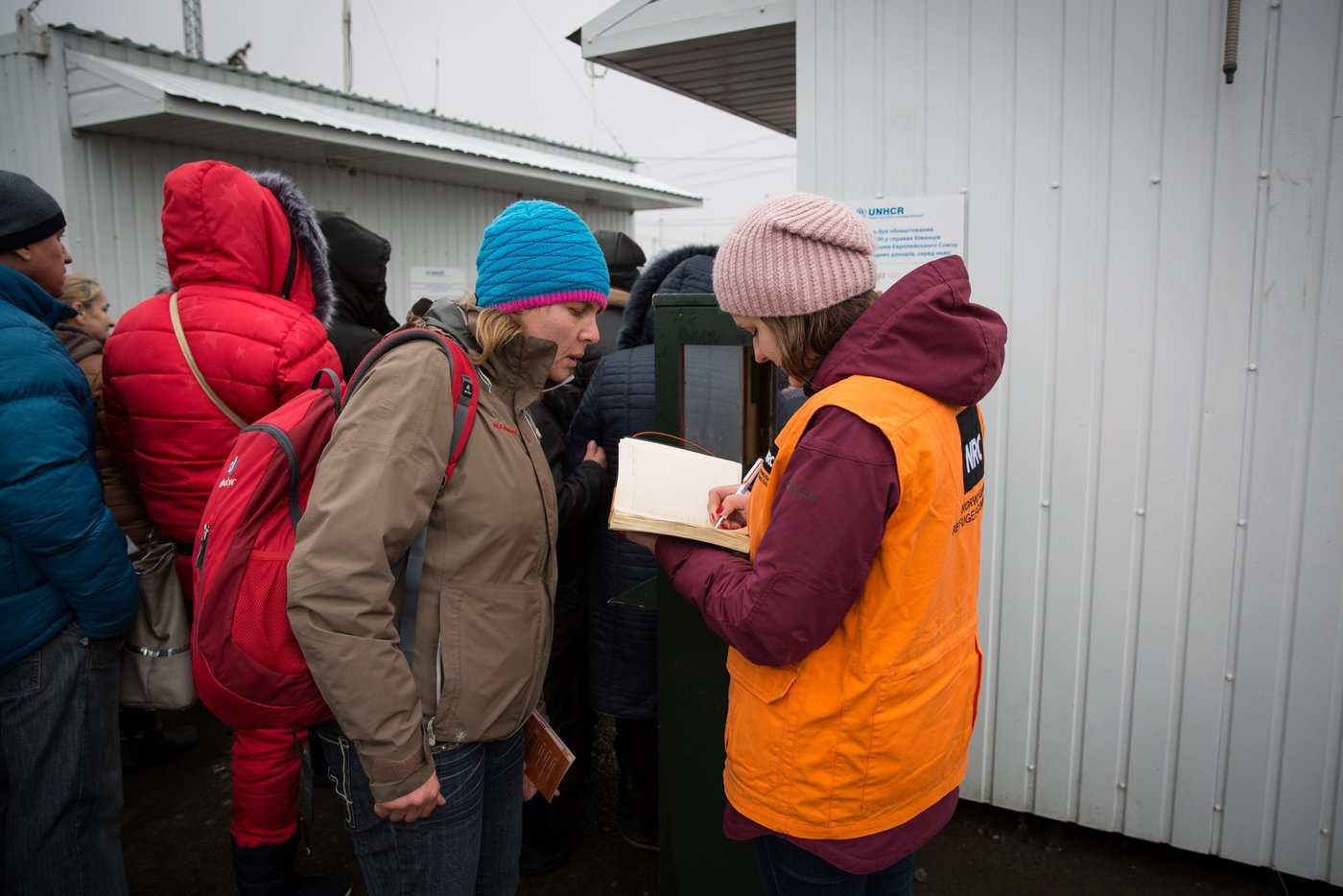 The entry/exit control point “Maiorsk” is one of four vehicle and pedestrian crossing points in Donetsk region. It is located about 20 km from the non-government controlled Horlivka town. The grey zone between the Ukrainian checkpoint and self-proclaimed “DPR” is the widest among all of the EECPs. After the ECCP was opened in early 2015 there was no bus connection in this corridor, people had to walk nearly 2-3 kilometres to take another bus. The situation changed in 2016, when it was agreed to launch bus shuttles. Over the period of its existence, the EECP has had many temporary closures due to escalation of the hostilities. Every day at least 7,000 people, mostly elderly, cross this entry-exit point to get their pension and social payments, visit their friends and relatives, buy essential goods. While crossing the contact line, concerned civilians are often exposed to serious security and safety risks such as minefields along the roads, periodic shelling and queuing at the checkpoints in harsh weather conditions for long hours.


50-year old ski-instructor Oksana is one of many people waiting for hours to cross the entry-exit point. 

“I left Alchevsk town on the non-government controlled area (92 km away) at 07:00 in the morning. It is afternoon, and I have not passed yet. There were times we were waiting for several days to cross, because of military hostilities. I currently live in government controlled Kharkiv with my husband. Comparing with other internally displaced people it is easier for me to adapt to new city, because I have my own apartment and job there. I am not planning to come back to my hometown, because there is no job for me there. Many people left, mostly elderly remained in the town”, -  says Oksana.  

In this picture Oksana talking to NRC communication officer Anastasiia Karpilianska

Photo: Ingebjørg Kårstad/NRC