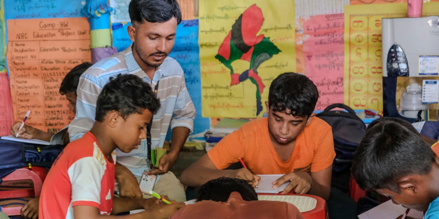 En lärare har uppsikt över sina två elever i klassrummet.