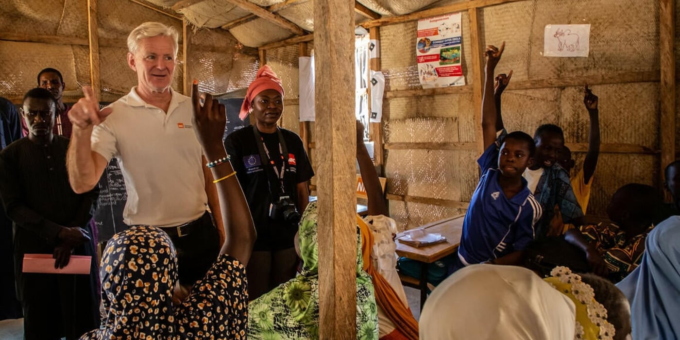 Jan Egeland in a classroom in Niger. He is asking the students a question and they are raising their hands to answer.