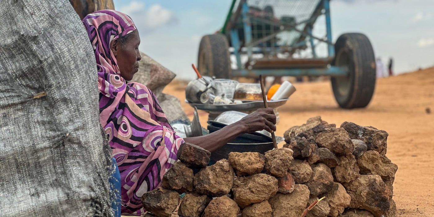 En kvinna sitter ner och lutar sig mot ett träd.
