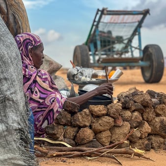 En kvinna sitter ner och lutar sig mot ett träd.