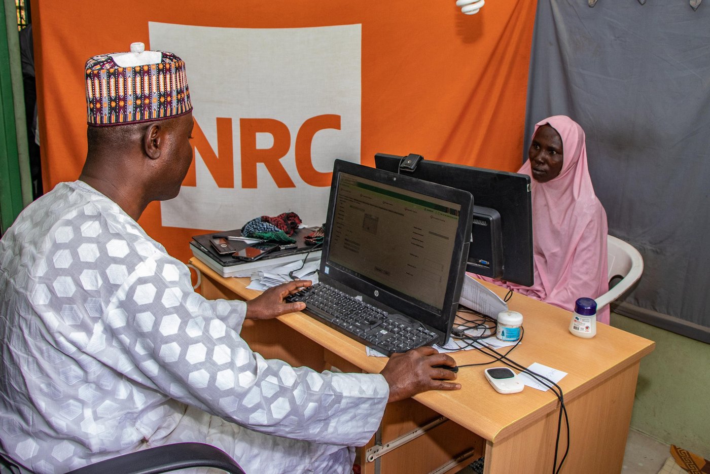 A government official from the National Identity Management Commission (NIMC) enters information in a computer for the ID card of a displaced woman named Modu Yagana in Maiduguri.
Photo: Samuel Jegede/NRC Nigeria