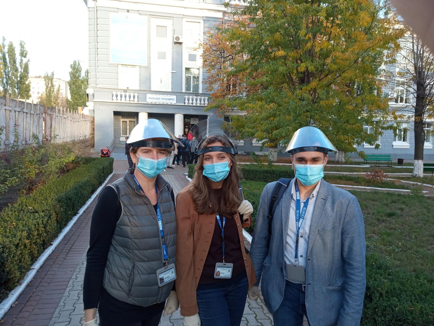 Three election observers in masks outside the polling station in Ukraine on election day.