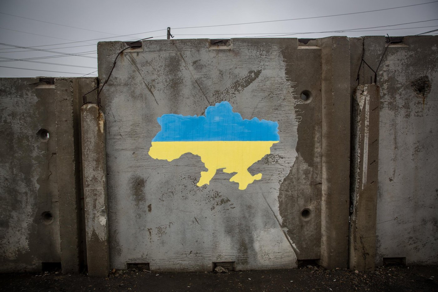 A map of Ukraine, before the war, painted on a wall at Maiorsk crossing point in Donetsk region.
The entry/exit control point “Maiorsk” is one of four vehicle and pedestrian crossing points in Donetsk region. It is located about 20 km from the non-government controlled Horlivka town. The grey zone between the Ukrainian checkpoint and self-proclaimed “DPR” is the widest among all of the EECPs. After the ECCP was opened in early 2015 there was no bus connection in this corridor, so people had to walk nearly 2-3 kilometres to take another bus. The situation changed in 2016, when it was agreed to launch bus shuttles. Over the period of its existence, the EECP has had many temporary closures due to escalation of the hostilities. Every day at least 7,000 people, mostly elderly, cross this entry-exit point to get their pension and social payments, visit their friends and relatives, buy essential goods. While crossing the contact line, concerned civilians are often exposed to serious security and safety risks such as minefields along the roads, periodic shelling and queuing at the checkpoints in harsh weather conditions for long hours.
Photo: Ingebjørg Kårstad/NRC