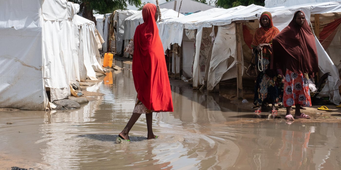 A young woman walks across a muddy path that resembles a river in Sharwari 5 camp in Maiduguri. The camp was one of the worst affected by the floods.