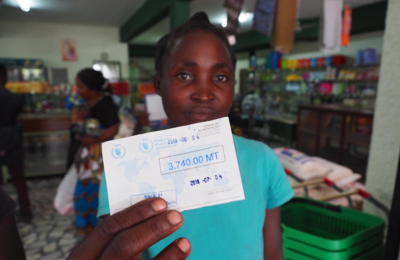 Beira, Mozambique (2019): Teresa Dolage holds up one of the vouchers she has received which gives her the opportunity to buy the items she needs from a local shop. The voucher is for 3.740 meticais (approx. $59) and the recipient has one month to spend the money. Most people spend it on food such as oil, rice, flour and ground nuts. (Photo: NORCAP/Ida Sem Fossvik)