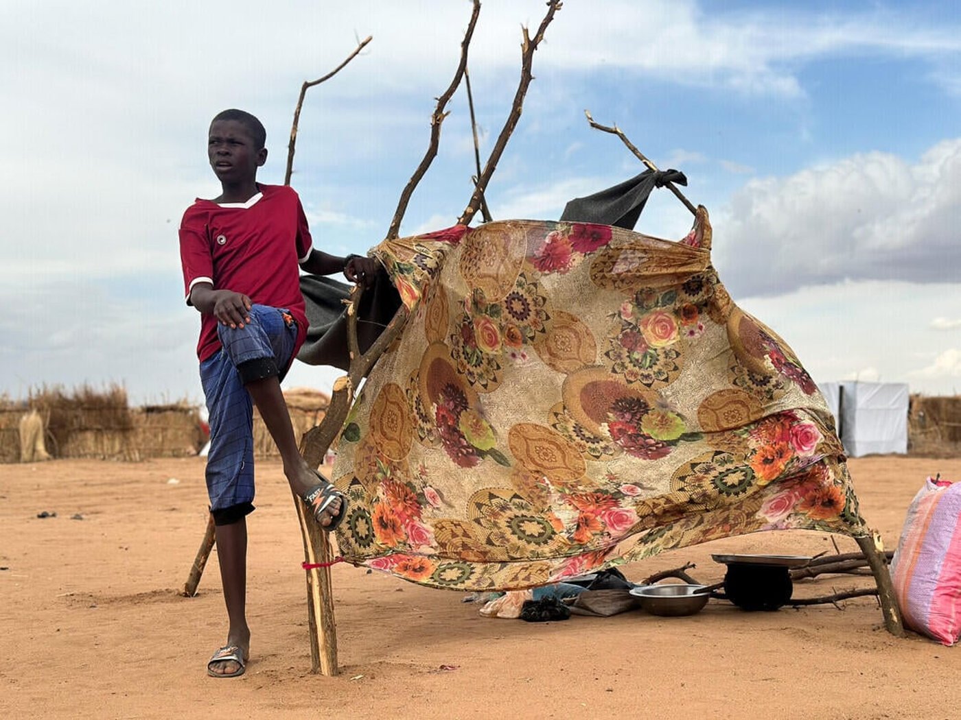 En pojke sitter vid sitt skydd i Tawila.