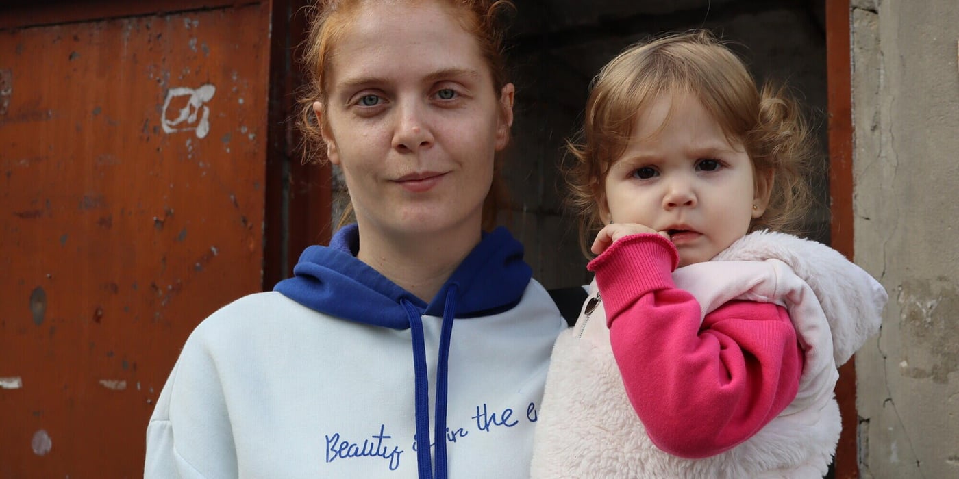 Anastasiia tillsammans med sin dotter utanför familjens hem i Derhachi i Charkivregionen. Huset skadades av beskjutning, och det är svårt att hålla det varmt under vintern. Foto: Inha Musiiuk/NRC