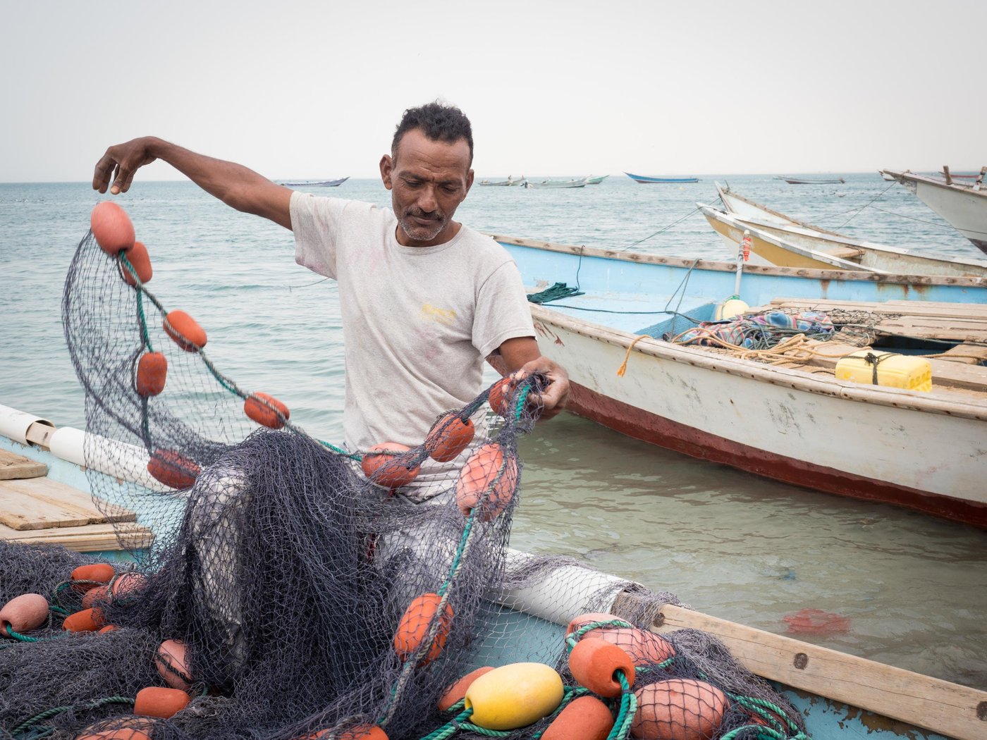 FISHERMAN 
Suleiman (45 years old) is a fisherman from Al-Hodeidah and now he is an internally displaced person in Ras Emran (Aden). His only income was fishing. Because of the war, he could not continue fishing in Al – Hodeidah after some of his friends were killed by airstrikes, and others were killed in the fish market which was hit by airstrikes several times. 

He is afraid to face his friends fate since they were killed without having committed any sins- they were only fishermen. Because of the war, he faced many difficulties in Al-Hodeidah, the high cost of living, no money to buy fishing tools and the fuel for the boat to go out to the sea.  Even before the war, his life was difficult and strenuous as he was staying   out at sea for many days, but at least it was a safe life.  Since the war started - he no longer feels safe.

When the clashes moved closer to the area where he lived, he heard people say that they should store basic food items because they would not be able to get out of their homes. Suleiman has a big family; one wife, 7 children and 2 grandchildren. He stored a few basic food items, which was enough for a few days. After a few days, the food was close to running out so he had to go out and buy some food and store it. He did this three times despite clashes coming to his area.  

One day, Suleiman made a tough decision – it was about surviving. He fled with his family, and they left with only the clothes that they were wearing. He sold his wife's jewellery and his animals to pay for transportation and travel expenses. He fled to Ras Emran (Aden) where he could continue work as a fisherman. It took three days to get here.

 As an internally displaced person he feels like a stranger in the area that he fled to. He cannot act or live as freely as he used to do in Al-Hodeidah before the war. He doesn't know the condition of his house in Al-Hodaidah. Maybe it was hit by an airstrike or is occupied by someone else.  But the most important thing for him is that he and his family are safe. 

Currently, Suleiman works together with other fishermen to provide a living for his family.  But it is not easy to find enough work. He has a wife, 7 children and 1 grandchild. He works for a daily fee between 3000 to 5000 Yemeni Riyals, and he needs many things   for his family to live as he and his family left everything behind when they fled.

Suleiman hopes that the war will end so he can return to his home. So that he can go back to his work. And his children can live in peace and safety like other children in the world and go back to school to finish their education. His message to the international community is to help and stand by Yemeni people in their ordeal and to do their best to stop this war in a peaceful manner and to make Yemen safe and secure for people.

Photo: Ingrid Prestetun/NRC